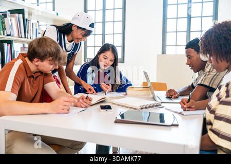 Multiethnic group of young students meeting at the library - multiethnic group of young students collaborating and studying diverse topics at a shared Stock Photo