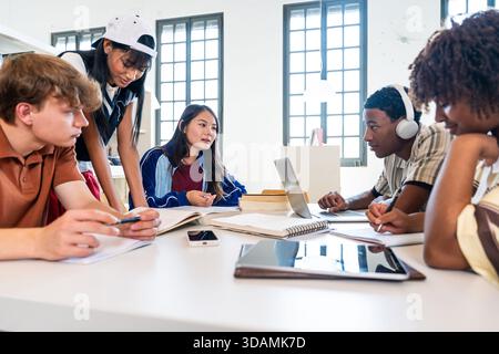 Multiethnic group of young students meeting at the library - diverse group of young students collaborating on their studies at a library table, utiliz Stock Photo