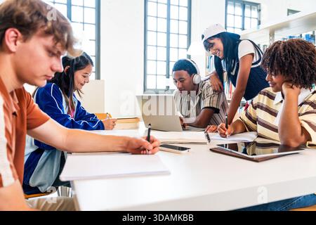 Multiethnic group of young students meeting at the library - multiethnic young students collaborating on their studies at a library table, using lapto Stock Photo