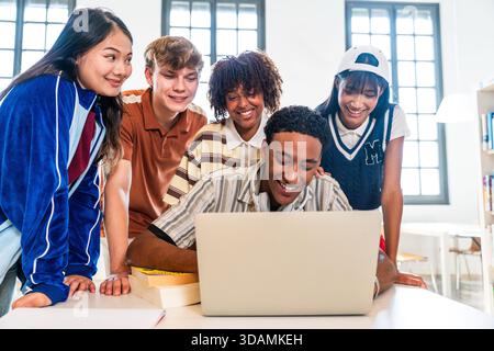 Multiethnic group of young students meeting at the library - young multiethnic people smiling while collaborating on a school project, watching conten Stock Photo