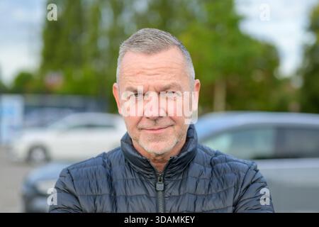 Portrait of a mature man in a black jacket looking confidently at the camera with a serious facial expression. Stock Photo
