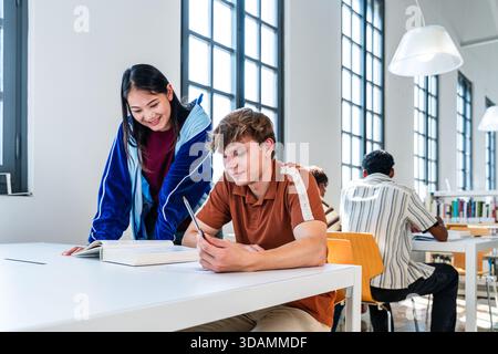Multiethnic group of young students meeting at the library - young multiethnic students collaborating on a school project, learning and doing research Stock Photo