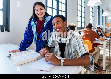 Multiethnic group of young students meeting at the library - young diverse students collaborating on academic tasks, learning and preparing for exams Stock Photo