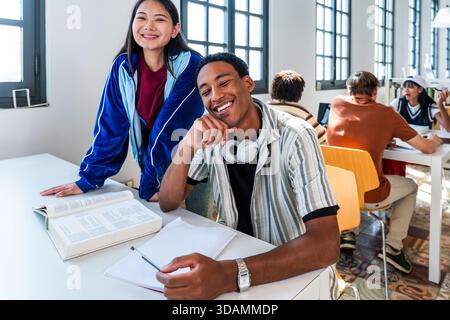 Multiethnic group of young students meeting at the library - young diverse students smiling during a study session, working together in a university l Stock Photo