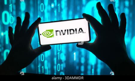 Hands holding smartphone displaying the nvidia logo against a digital blue background, New York City, 08 December 2025 Stock Photo