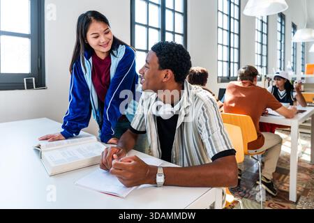 Multiethnic group of young students meeting at the library - multiethnic young students collaborating and studying together in a bright, modern librar Stock Photo
