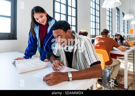 Multiethnic group of young students meeting at the library - young multiethnic students collaborating on a school project, learning and doing homework Stock Photo