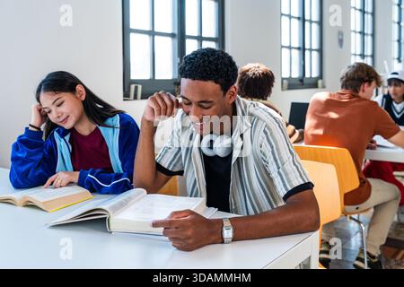 Multiethnic group of young students meeting at the library - group of diverse young students learning and collaborating in a university library, focus Stock Photo