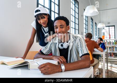Multiethnic group of young students meeting at the library - happy multiethnic students reading books and working on a project in a library. Diverse g Stock Photo