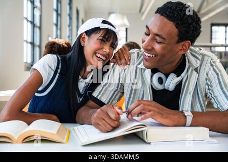 Multiethnic group of young students meeting at the library - young multiethnic students studying together, sharing a happy moment and laughing while l Stock Photo
