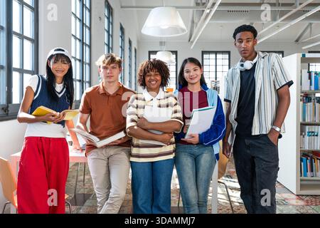 Multiethnic group of young students meeting at the library - diverse group of young students posing for a portrait in a modern university library, hol Stock Photo