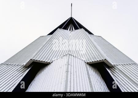 View of striking geometric architecture with corrugated silver panels and stark black accents reaching toward the sky, Reynisfjara Beach, Vik, Iceland Stock Photo
