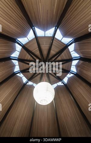 View of an interior wooden structure with a light fixture hanging from the ceiling and skylight above, Reynisfjara Beach, Vik, Iceland. Stock Photo