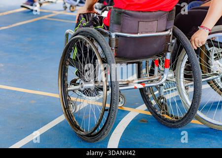 Close-up of high-performance wheelchair athletes competing on a blue sports court. Shows effort and overcoming adversity. Stock Photo