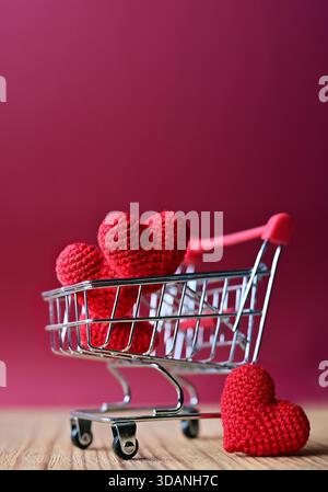 The red Heart shapes in shopping cart on red background , love concept for shopping on valentines day. Stock Photo