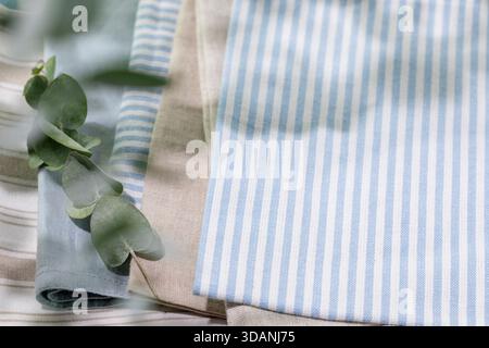 Striped Cotton Napkins On Linen Tablecloth With Eucalyptus Branch And Soft Natural Light. Perfect For Eco-Friendly Kitchen Designs, Home Decor Mockups Stock Photo