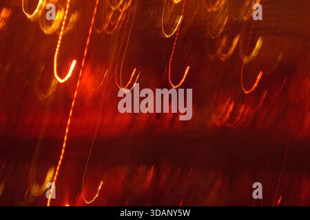 Abstract dancing red light trails background. Rhythmic curved neon streaks texture perfect for music, jazz or party themes. Stock Photo