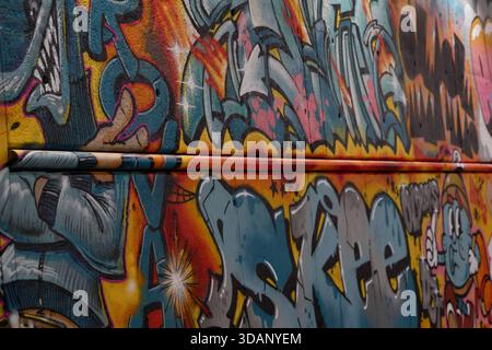 Close-up of colorful graffiti lettering and abstract shapes on a textured concrete underpass wall at Dijksgracht, Amsterdam, Netherlands, at night. Stock Photo