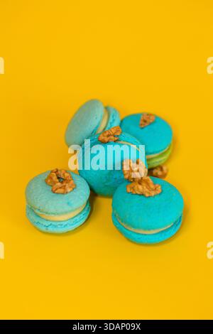 Blue macaroons on a yellow plain background, with walnuts Stock Photo