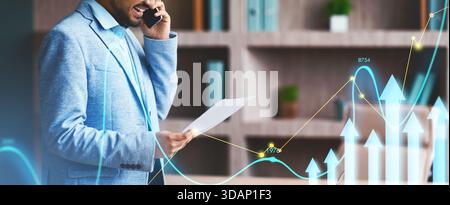 Successful Indian Businessman Discussing Paperwork Over Phone in Modern Office Setting Stock Photo