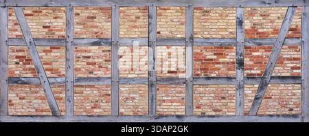 Wide timber frame made of gray beams infilled with brick stones Stock Photo