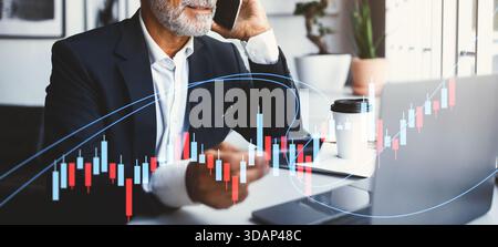 Senior Businessman Using Smartphone and Laptop for Online Transactions in Modern Office Stock Photo