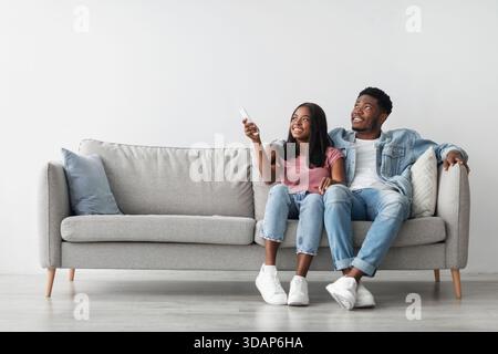 Young black woman switching on air conditioning at her home Stock Photo