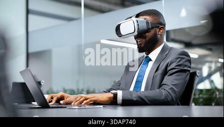 Businessman Uses Virtual Reality Headset While Working at Desk in Modern Office Space Stock Photo