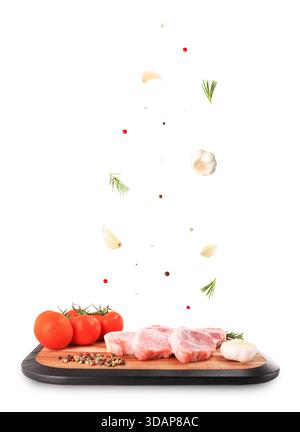 Raw pork steaks with flying garlic, rosemary and spices on a wooden board isolated on white background. High quality photo Stock Photo