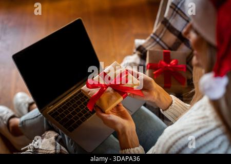 Gift Wrapping Session at Home During Christmas Time With a Cozy Atmosphere and a Laptop Nearby Stock Photo