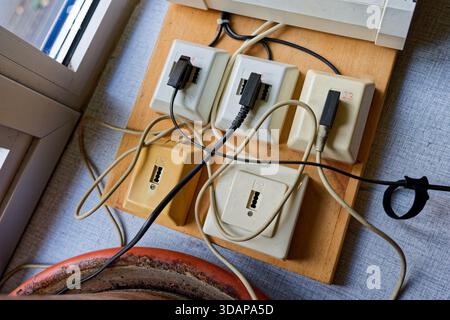 A small wooden plate holds five ancient German TAE connectors with colored leads, the improvised panel looks handmade and practical as each wire lines Stock Photo