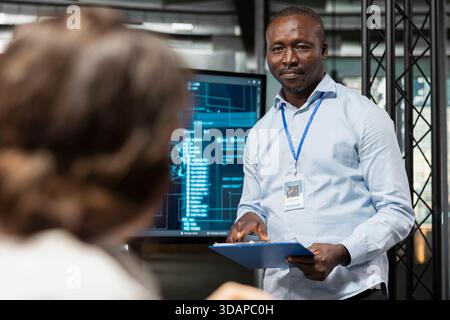 Startup manager discussing AI tech roadmap with workers during briefing session. African american man and colleagues analyzing system performance metrics after QA testing Stock Photo