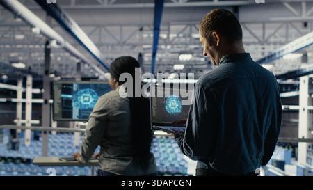 Data center software developers monitor deep learning processes, reviewing operational metrics. Server farm IT specialists work together to review neural networks reports during inspection, camera B Stock Photo