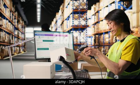 Asian male staff uses handheld scanner to register airway bill information, updating the package tracking software in real time with barcode reader and shipment details. Stock room. Camera A. Stock Photo