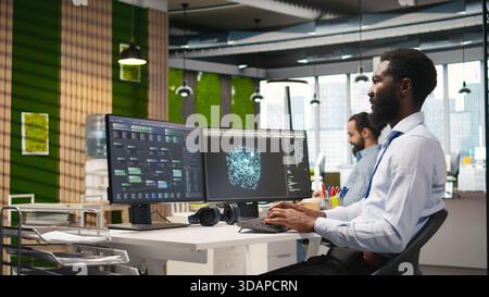 Programmer optimizing performance using AI LLM chatbot recommendations. African american worker uses artificial intelligence assistant to convert manual workflows into automated scripts, camera A Stock Photo