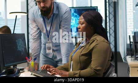 Pleased startup office manager applauding female programmer for optimizing code using AI. Satisfied team leader offering positive feedback to work done by IT specialist in office, camera A Stock Photo
