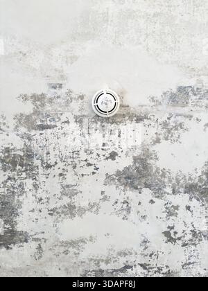 Round ceiling sprinkler nozzle in minimalistic concrete ceiling with chipped paint and abstract structure, Wuppertal, Germany Stock Photo