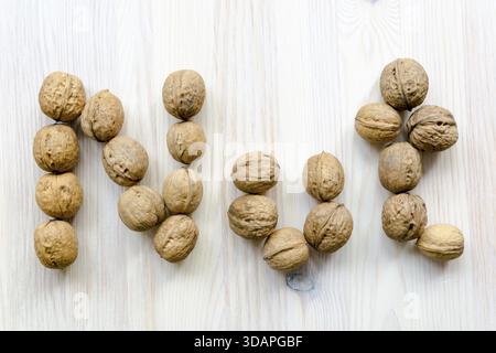 Word nut made from many walnuts on the light wooden background Stock Photo