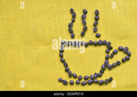 Coffee cup with aroma smoke jets made of raw coffee beans on the yellow tablecloth Stock Photo