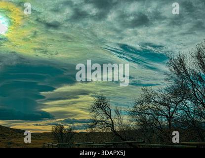 Storm sky with sunlight thick swirling clouds offers view from land of heavens above during dramatic wind storms over Wyoming. Land is in shadow. Stock Photo