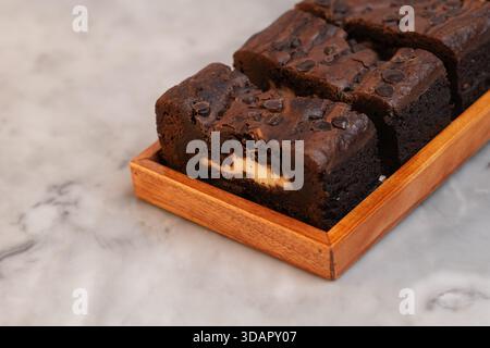 Chocolate banana loaf, sliced, on wood tray, marble backdrop Stock Photo