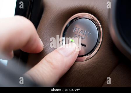 Close-up of a finger pressing a car engine start-stop button, symbolizing modern automotive technology, convenience, smart vehicle systems, innovation Stock Photo
