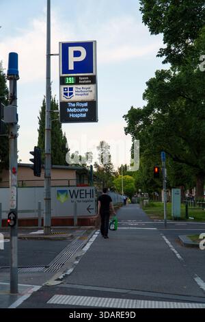 Melbourne, VIC, Australia. December 11, 2025. - A person walks on a footpath past a large digital sign for The Royal Melbourne Hospital car park, indi Stock Photo