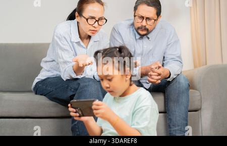 Smart phone addiction. Stressed parent talking about the issue of their daughter having a gaming addiction. Selective focus on parent. Stock Photo
