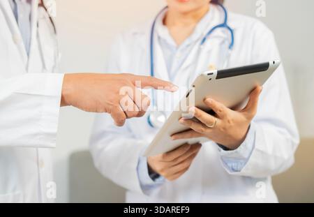 Two doctors working together using a digital tablet discuss patient anamnesis or checkup results together. Health care teamwork concept. Stock Photo