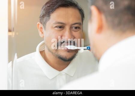 Getting my smile ready.  Back side shot of a handsome adult man brushing his teeth in bathroom. Stock Photo