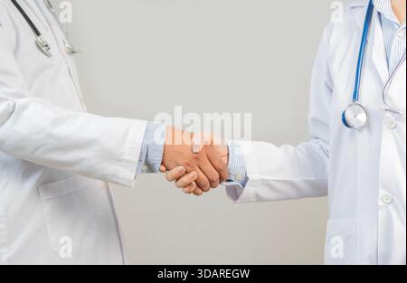 Two doctors are shaking hands in meeting room or medical office and support in team at hospital for healthcare. Medical people concept. Stock Photo