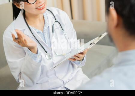 Young doctor asking senior impaired male patient to sign insurance policy at home. Senior Medical Check-Up Stock Photo