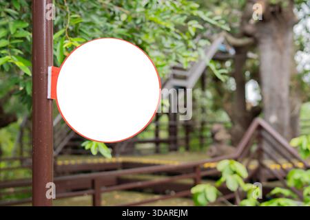 Rustic Wooden Circle Sign Hanging. Round sign on a steel pole in Lush Green Tropical Foliage. Copy space. Stock Photo