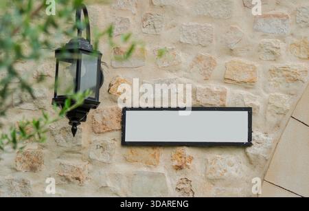 Selective focus of beige brick wall with white empty billboard for writing nearby is an old lamp hanging on the wall. Stock Photo